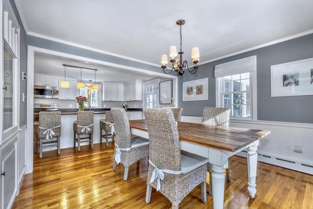 dining space featuring crown molding, a chandelier, and light hardwood / wood-style flooring