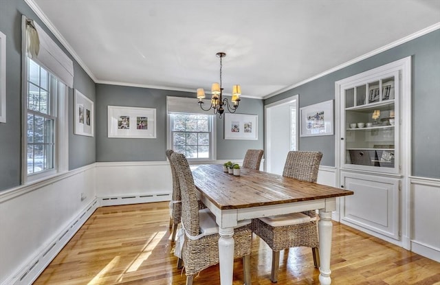 dining room featuring crown molding, light hardwood / wood-style floors, built in features, and a baseboard heating unit