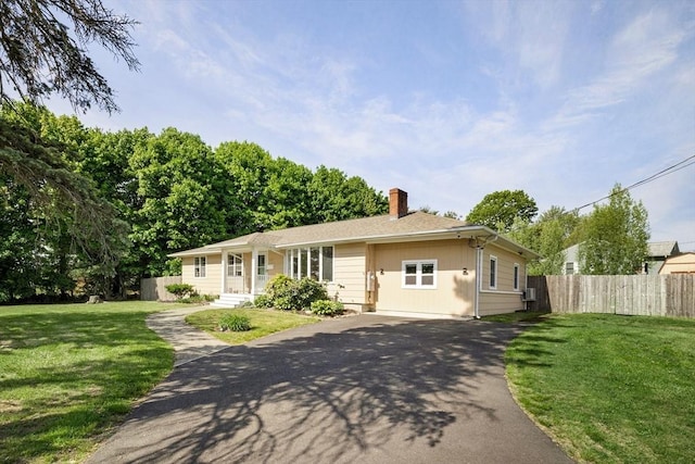 view of front of house featuring a chimney and asphalt driveway