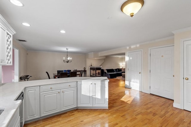 kitchen featuring a chandelier, light hardwood / wood-style floors, decorative light fixtures, white cabinets, and ornamental molding