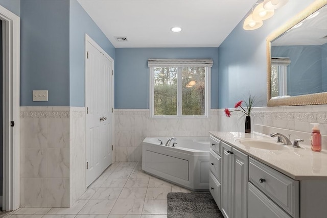 bathroom featuring vanity, a tub to relax in, and tile walls