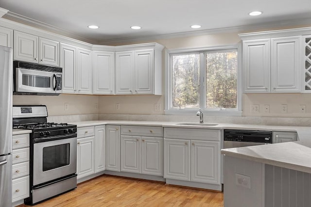 kitchen with white cabinets, crown molding, sink, appliances with stainless steel finishes, and light hardwood / wood-style floors