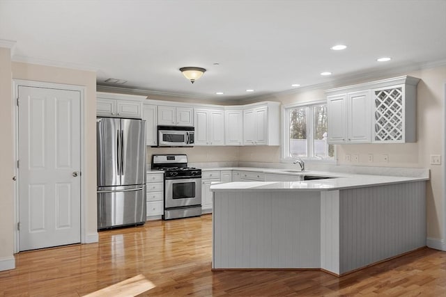 kitchen with kitchen peninsula, white cabinetry, light hardwood / wood-style floors, and appliances with stainless steel finishes