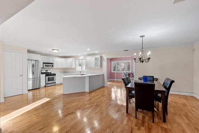 dining area featuring ornamental molding, light wood-type flooring, a notable chandelier, and sink