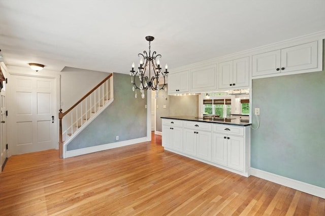 14 Prince St, Danvers, MA 01923 - kitchen featuring light wood-style floors, dark countertops, baseboards, white cabinets, and a chandelier