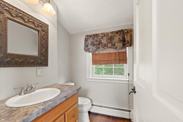 14 Prince St, Danvers, MA 01923 - half bath with a baseboard heating unit, toilet, vanity, and wood finished floors