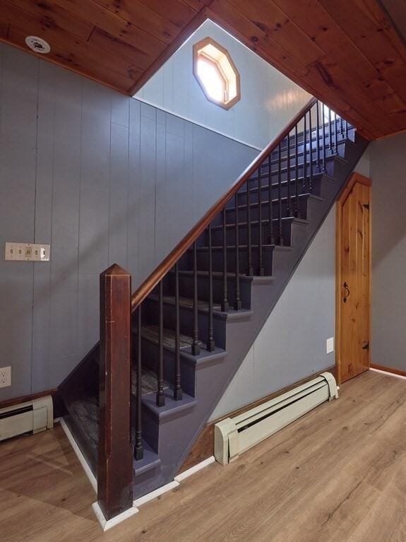 stairs featuring a baseboard radiator, wood-type flooring, and wooden ceiling