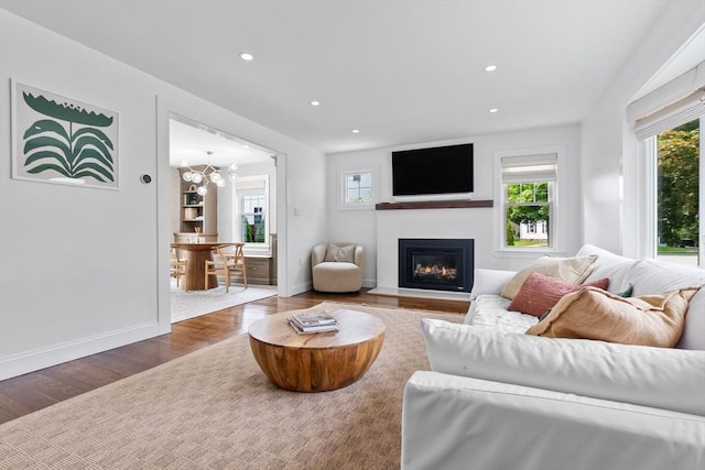 71 Sheffield Rd, Melrose, MA 02176 - living area with healthy amount of natural light, wood finished floors, a glass covered fireplace, recessed lighting, and a chandelier
