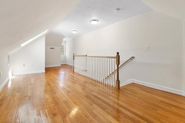 bonus room featuring light wood-style floors, baseboards, lofted ceiling, and visible vents