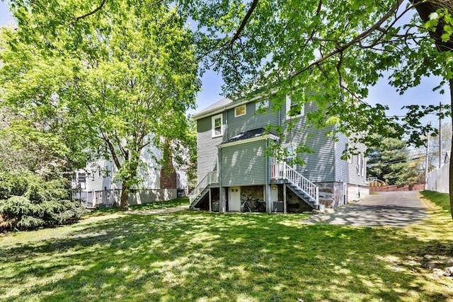 back of property featuring stairs, a lawn, and fence