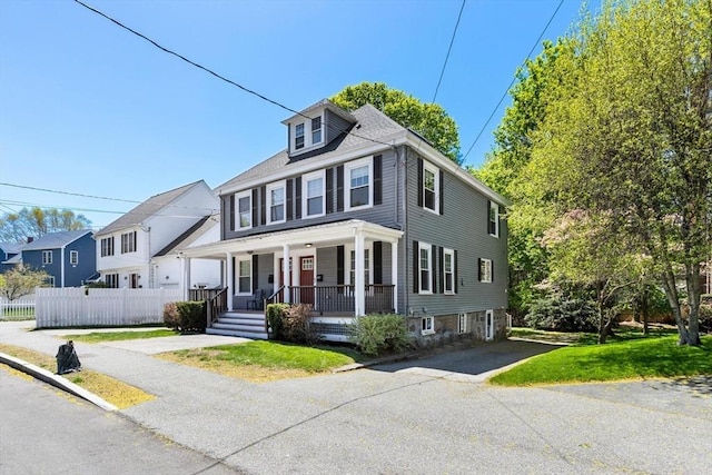 traditional style home featuring fence, covered porch, and aphalt driveway