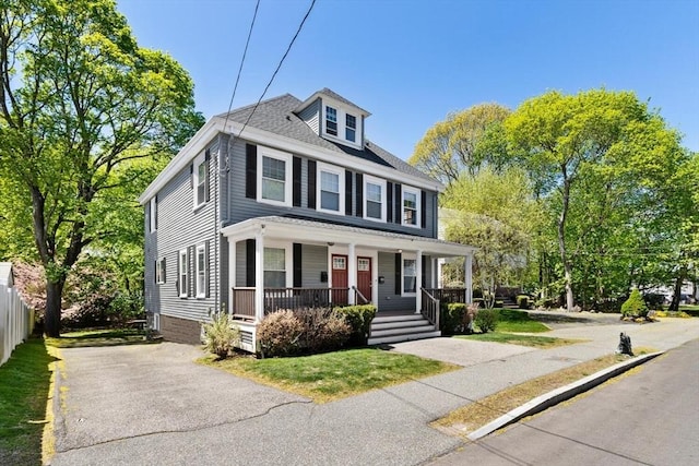 american foursquare style home featuring a porch and fence