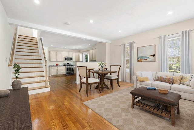 living room featuring light wood-style floors, recessed lighting, and stairs