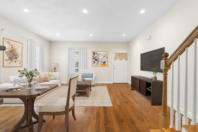 living room with recessed lighting, baseboards, wood finished floors, and stairway