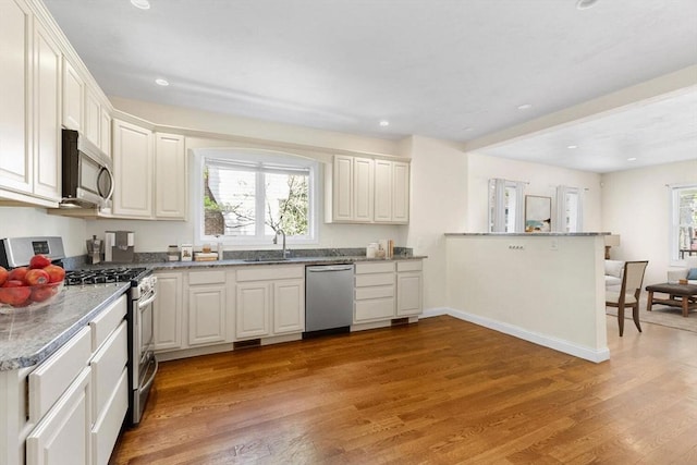 kitchen featuring a healthy amount of sunlight, appliances with stainless steel finishes, light wood-style flooring, and a sink