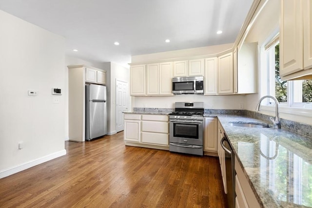 kitchen featuring a sink, light stone counters, dark wood-style floors, stainless steel appliances, and recessed lighting