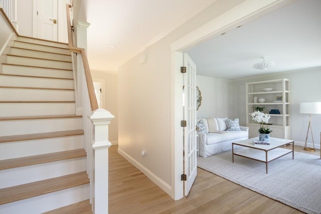 staircase featuring crown molding, baseboards, and wood finished floors