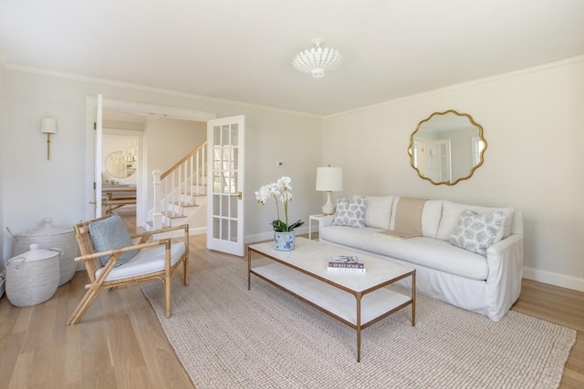living room featuring stairs, baseboards, ornamental molding, and wood finished floors