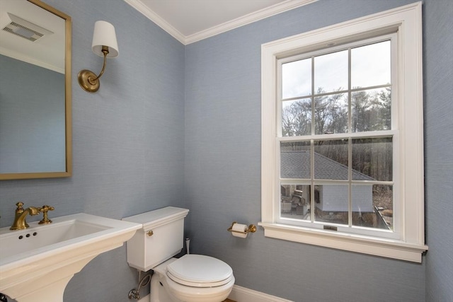 half bathroom featuring visible vents, ornamental molding, toilet, baseboards, and a sink
