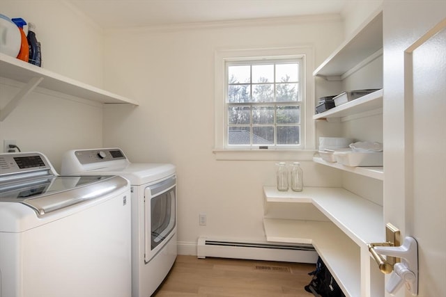 clothes washing area featuring washer and dryer, crown molding, laundry area, light wood finished floors, and a baseboard radiator
