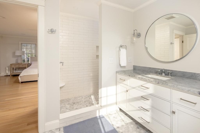 ensuite bathroom with crown molding, vanity, wood finished floors, walk in shower, and ensuite bath