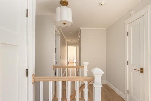 hall with crown molding, baseboards, light wood-type flooring, and an upstairs landing