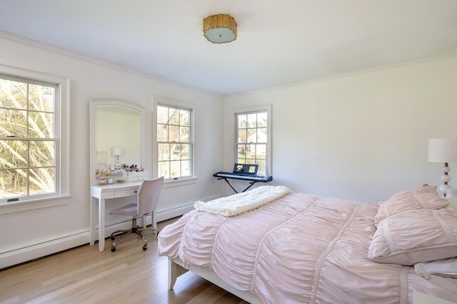 bedroom with ornamental molding, baseboard heating, and light wood-type flooring