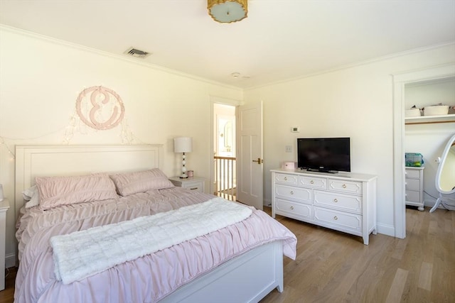 bedroom with crown molding, visible vents, and wood finished floors