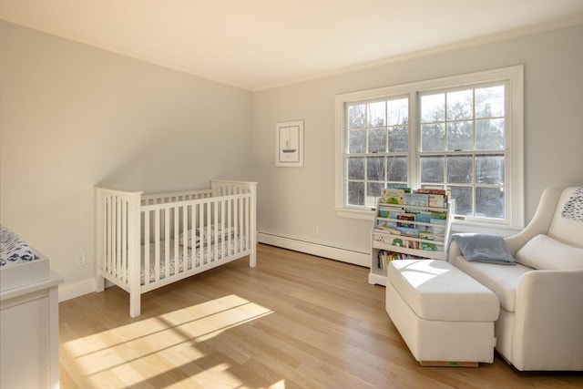 bedroom with baseboards, a baseboard radiator, ornamental molding, and wood finished floors