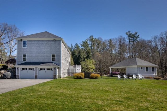 view of side of home with a lawn, fence, driveway, and a garage