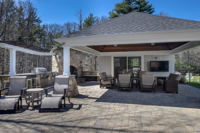 view of patio featuring an outdoor fireplace, fence, area for grilling, an outdoor kitchen, and a gazebo