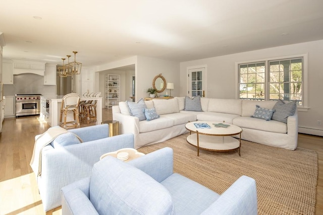 living area with light wood-style floors, baseboard heating, and a chandelier