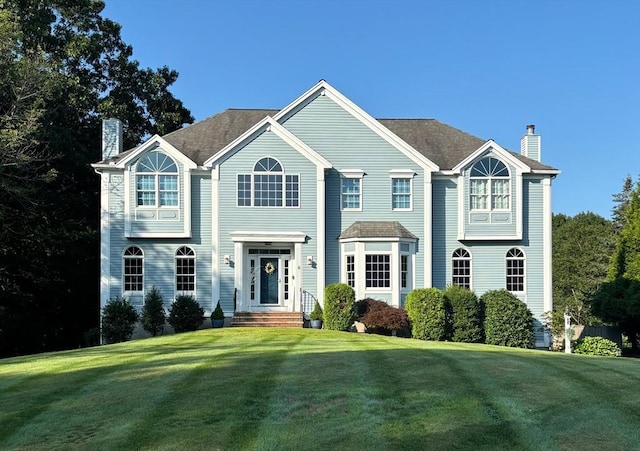 view of front facade with a front yard and a chimney