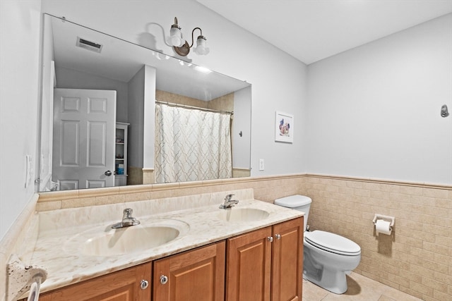 bathroom with toilet, vanity, tile walls, and tile patterned flooring