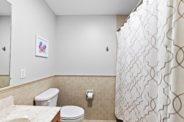 bathroom featuring toilet, vanity, and tile walls