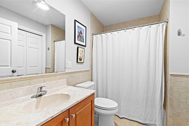 bathroom with a shower with shower curtain, toilet, tile patterned floors, tile walls, and vanity