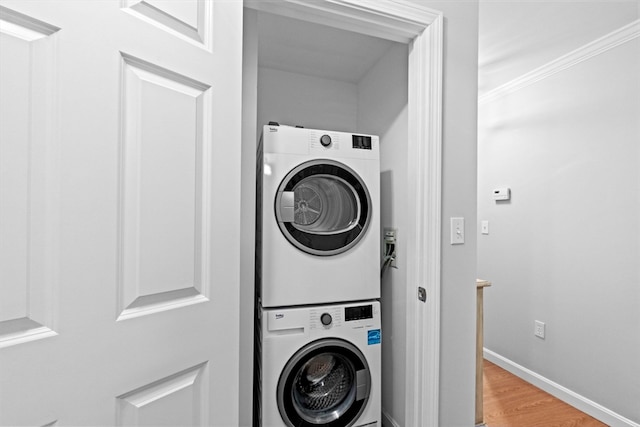 washroom featuring ornamental molding, hardwood / wood-style flooring, and stacked washer / dryer