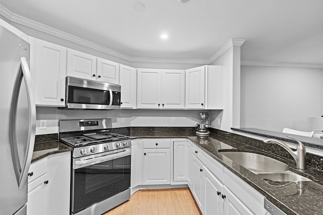 kitchen featuring crown molding, appliances with stainless steel finishes, light hardwood / wood-style flooring, and white cabinetry