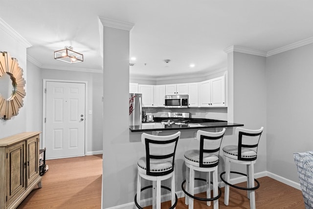 kitchen featuring appliances with stainless steel finishes, kitchen peninsula, white cabinetry, and light hardwood / wood-style floors