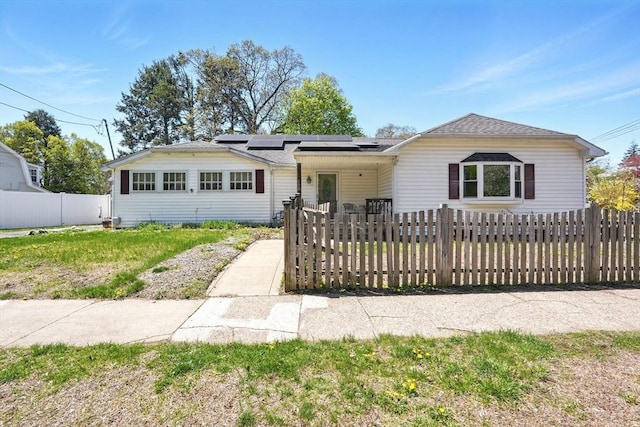 ranch-style home with a fenced front yard and solar panels