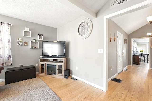 living area featuring baseboards, visible vents, and light wood finished floors