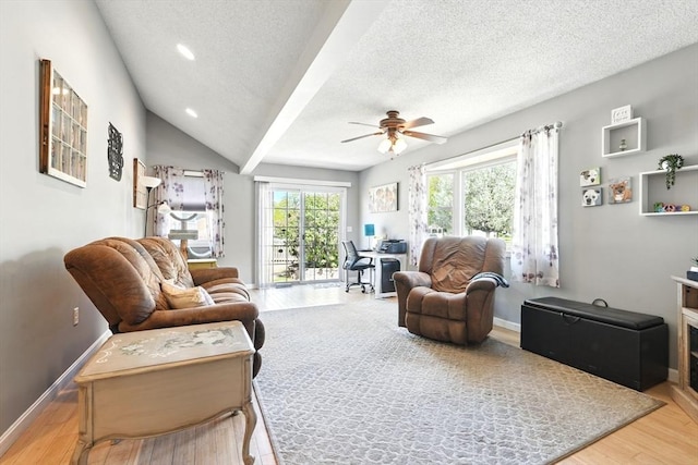 living area featuring baseboards, a ceiling fan, a textured ceiling, and wood finished floors