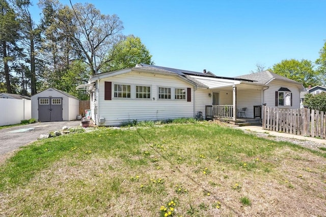 view of front of property featuring an outdoor structure, fence, a storage shed, and a front yard