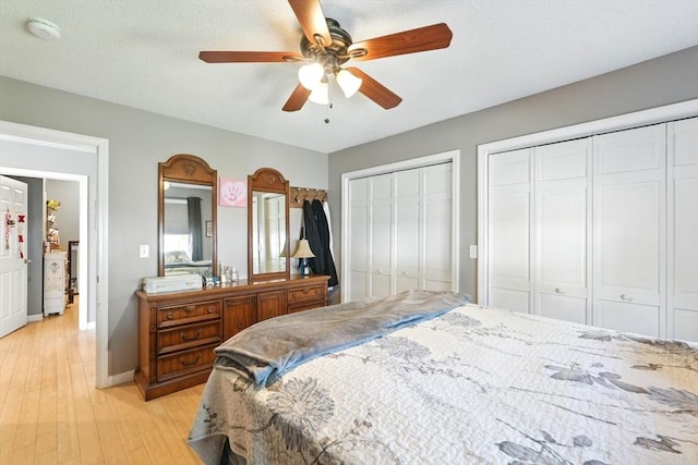 bedroom with ceiling fan, multiple closets, baseboards, and light wood-style flooring