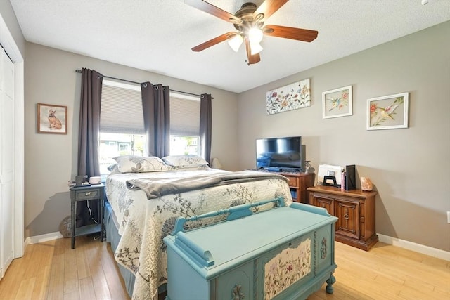bedroom featuring baseboards, ceiling fan, light wood finished floors, and a closet