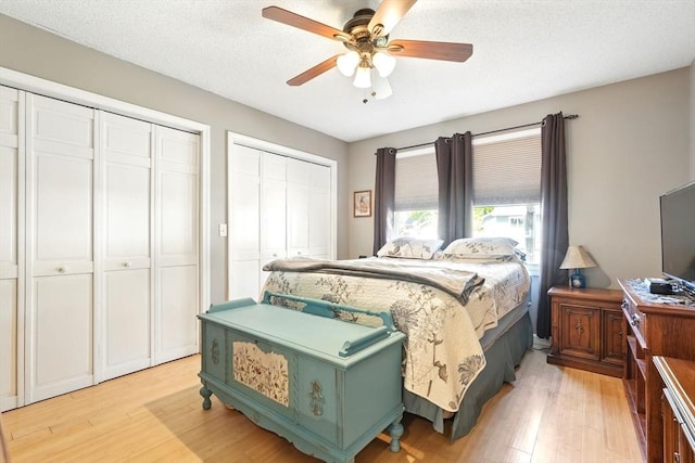 bedroom with light wood-style flooring, multiple closets, and ceiling fan