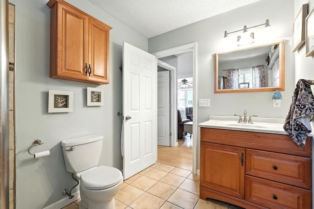 bathroom featuring vanity, toilet, ceiling fan, a textured ceiling, and tile patterned floors
