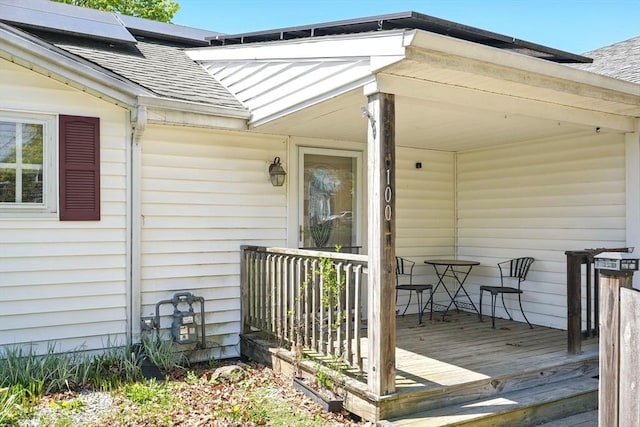entrance to property featuring a porch and a shingled roof