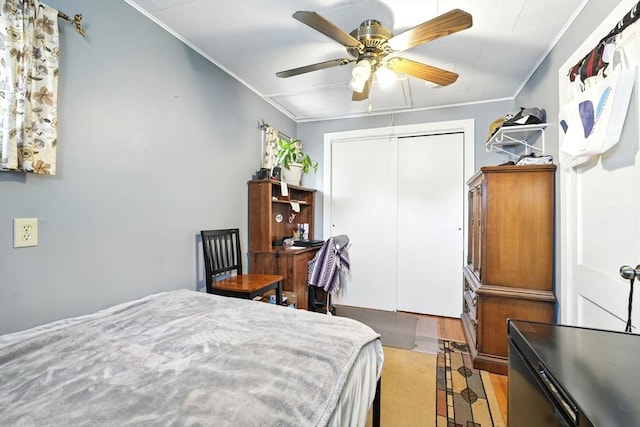 bedroom with a ceiling fan, ornamental molding, wood finished floors, and a closet