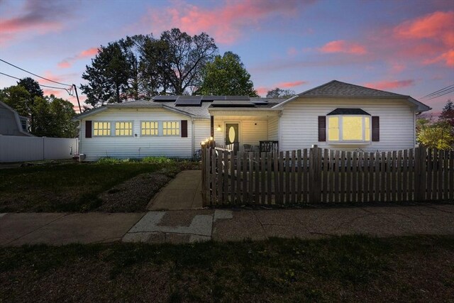 view of front of property with roof mounted solar panels and a fenced front yard